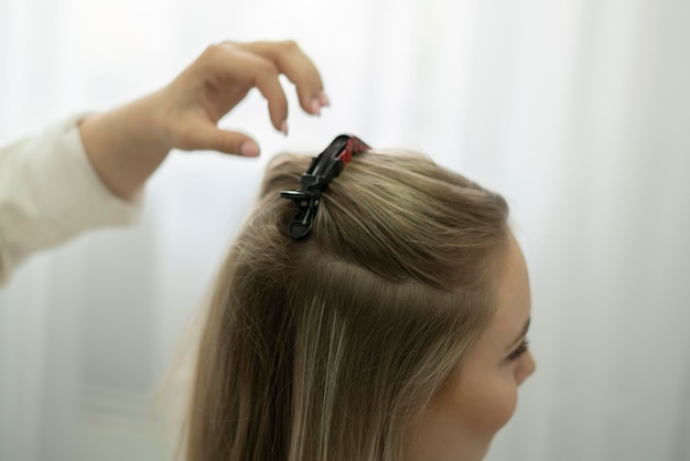 Een professionele kapper zet een haarspeld in het haar van de vrouw in de salon.