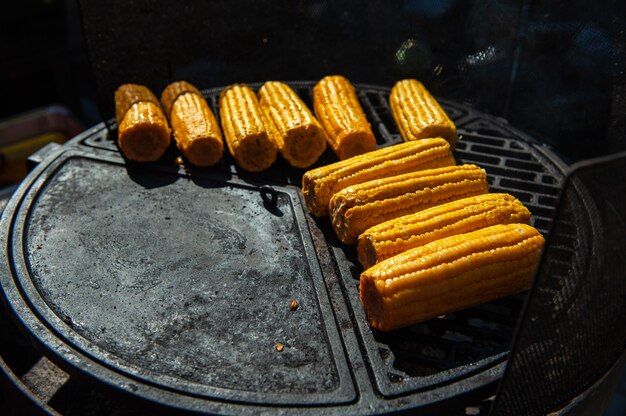 Een professionele kok bereidt maïs op de grill, outdoor-, food- of cateringconcept