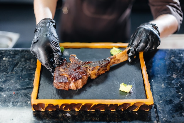 Een professionele kok serveert prachtig een sappige gegrilde steak met boter en kruiden