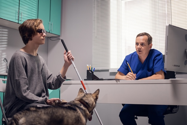 Foto een professionele mannelijke dierenarts die een geleidehond in een dierenartskliniek onderzoekt.