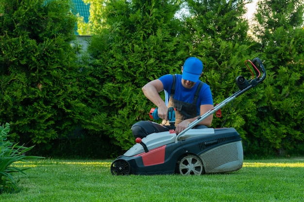 Een professionele reparateur repareert een grasmaaier Een man repareert een maaier in zijn achtertuin