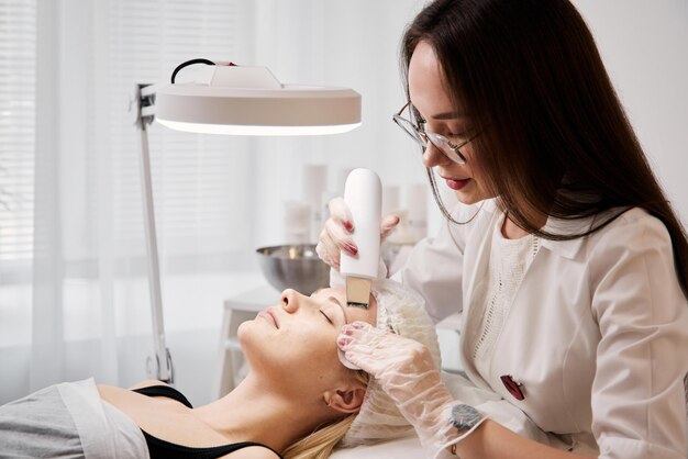 Een professionele schoonheidsspecialiste voert een mechanische gezichtsreinigingsprocedure uit in de spa Mooie blanke vrouw op een cosmetische procedure gezondheidscentrum