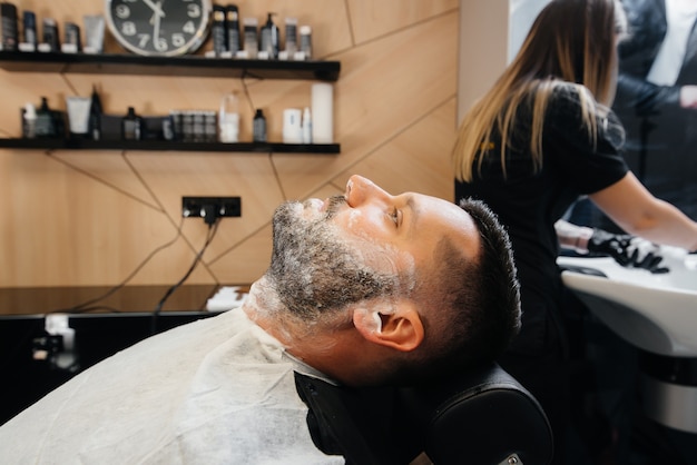 Een professionele stylist in een moderne, stijlvolle kapperszaak scheert en knipt het haar van een jonge man. schoonheidssalon, kapsalon.