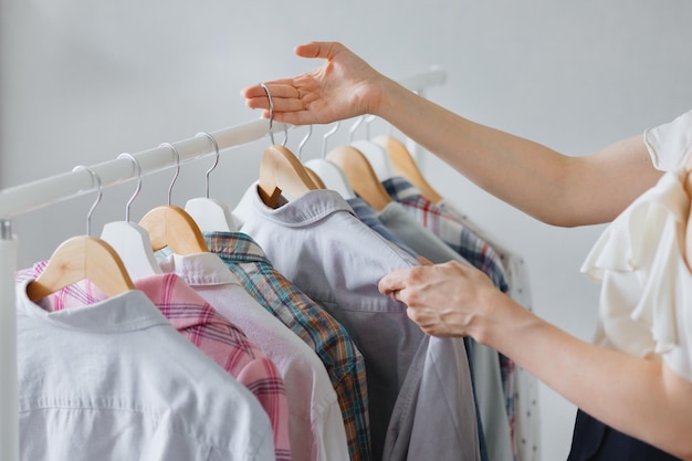 Een professionele stylist van een Europese vrouw met donker haar en een bril kiest kleding voor een bedrijf