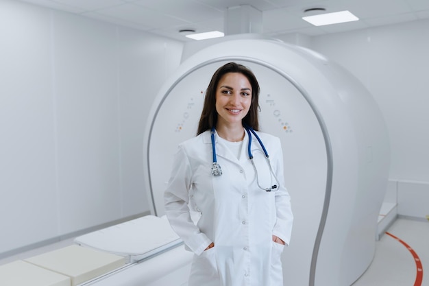 Een professionele verpleegster in een witte jas in een CT-scankamer De vrouw lacht en kijkt naar de camera