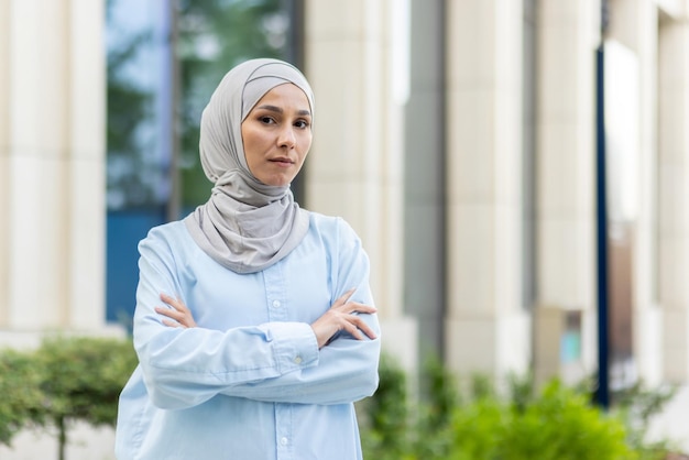 Foto een professionele vrouw in een hijab staat zelfverzekerd met haar armen gekruist in een moderne stad