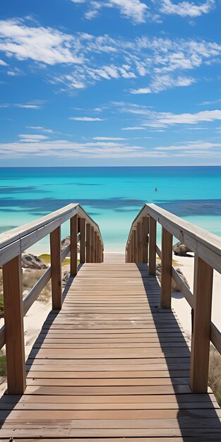 een promenade leidt naar een strand met een blauwe hemel en een boot op de achtergrond