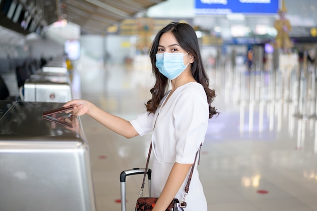 Een reizende vrouw draagt een beschermend masker op de internationale luchthaven, reist onder Covid-19 pandemie,