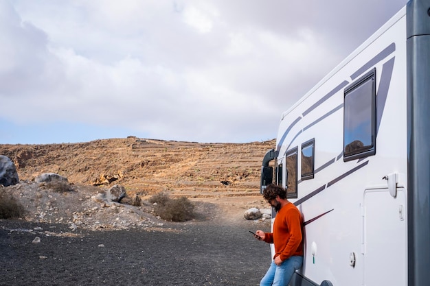 Een reiziger die een telefoon-app gebruikt buiten een moderne grote camper om een roadtrip en de volgende bestemming te plannen op een technologie-smartphone-app Concept van schilderachtige plek en reislevensstijl Voertuig huren