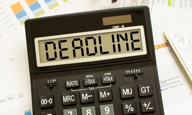 Een rekenmachine met het label DEADLINE ligt op financiële documenten op kantoor