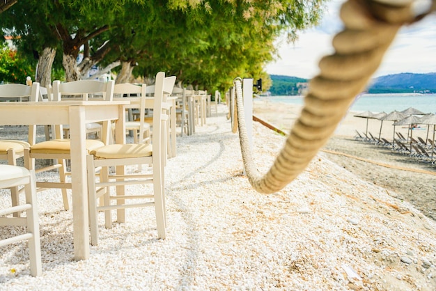 Een restaurant met een touwschommel en stoelen op het strand