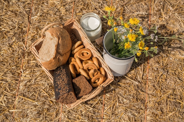 Een rieten mand met brood voor een picknick in het veld en een blikje verse melk.
