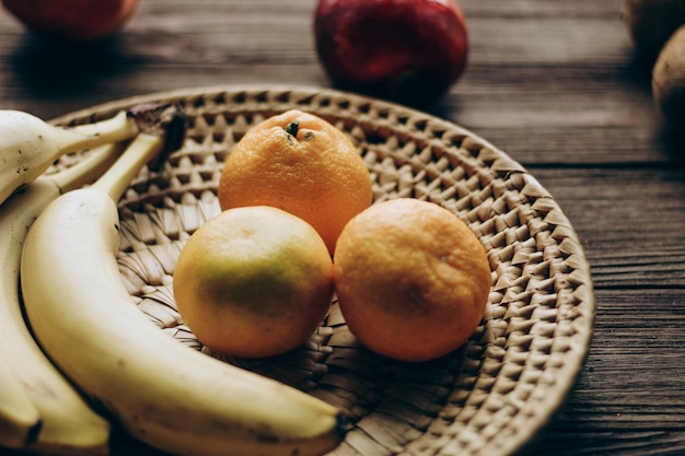 Een rieten schaal met fruit staat op een houten bruine tafel