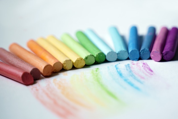 Foto een rij droge pastelkleuren met een regenboog getekend op wit papier