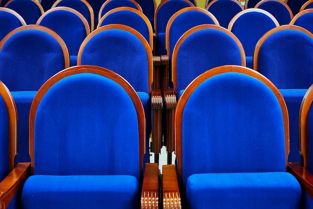 Een rij fluwelen blauwe fauteuils met houten armleuningen in de meeti