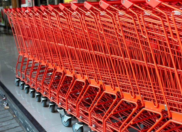 Een rij rode winkelwagentjes in een moderne supermarkt