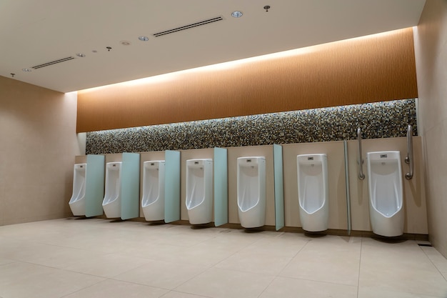 Een rij witte urinoirs in een betegelde muur in een openbaar toilet