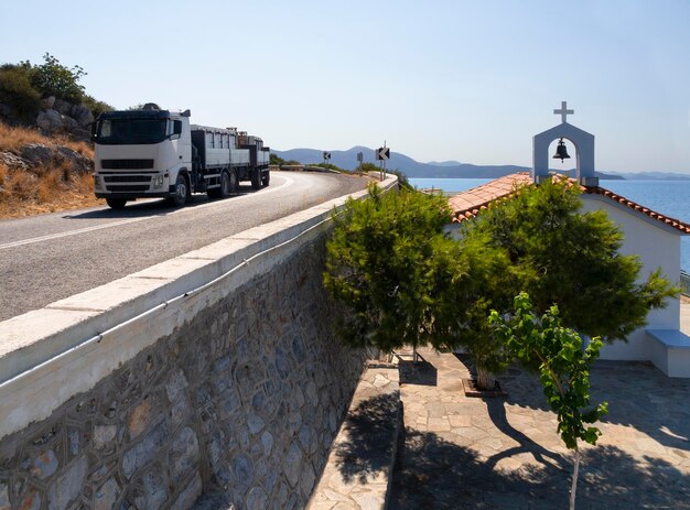 Een rijdende vrachtwagen en uitzicht op de Griekse kerk van Evia in Cycladische stijl in Griekenland op een zonnige dag