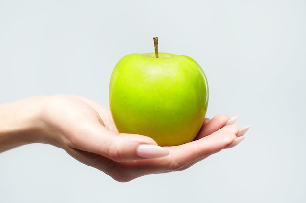 Een rijpe groene appel in de palm van de hand van een jonge vrouw