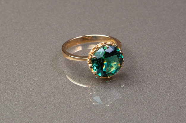 Een ring van groene saffier met een gouden band en een kleine groene edelsteen.