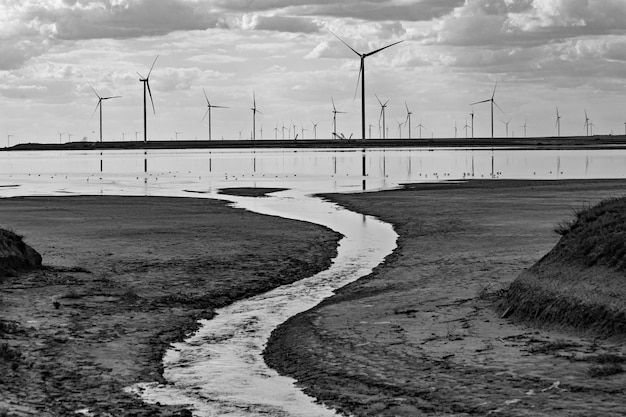 Een rivier stroomt door een veld van windturbines.