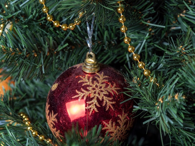 Een rode bal met een sneeuwvlok aan de kerstboom. Het concept van nieuwjaar en Kerstmis