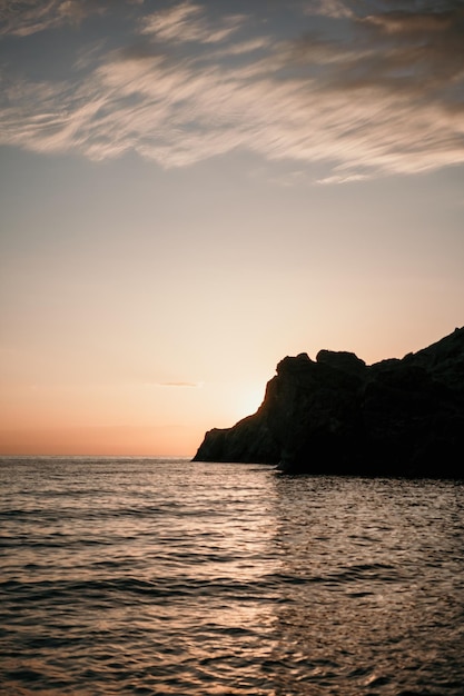 Een rode brandende zonsondergang boven de zee met rotsachtige vulkanische klif Abstracte natuur zomer of lente oceaan zee achtergrond