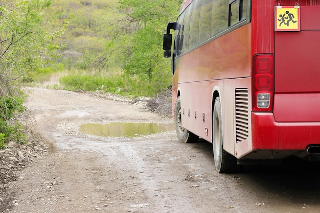 Een rode bus met kinderen. Vervoer van passagiers. Vervoer van kinderen. Een waarschuwingsbord voor kinderen op de achterkant van de bus.