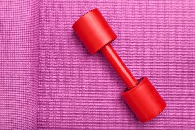 Een rode halter liggend op een rubberen gymnastiekmat close-up