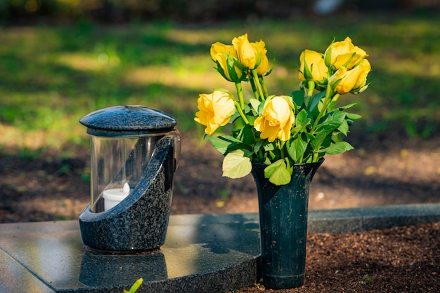 Een rode kaars op de grafstenen met bloemen