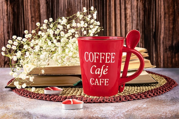 Een rode koffiemok met de woorden coffee cafe erop Boeken gypsophila bloemen kaarsen als decor