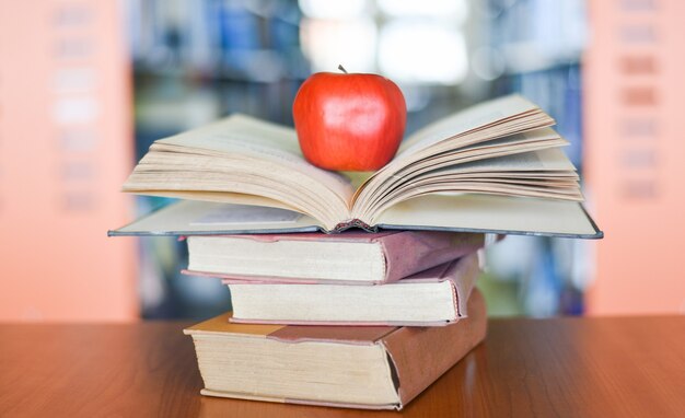 Een rode rijpe appel op een stapel boeken