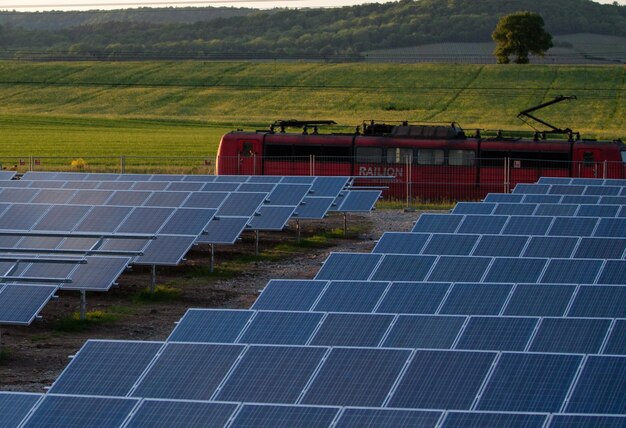 Foto een rode trein passeert voor zonnepanelen.