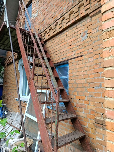 Een roestige metalen trap aan de zijkant van een bakstenen gebouw