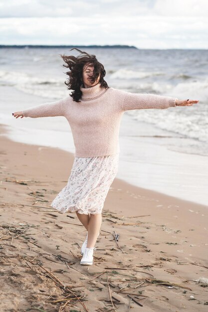Foto een romantisch meisje geniet van de wind bij de zeedans van een gelukkige man op de oceaanvrouw in een lichte jurk