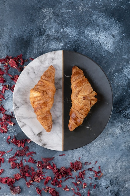 Een rond bord met verse croissants op een marmeren tafel.