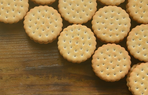 Een rond broodje met kokosnootvulling ligt in grote hoeveelheden op een bruin houten oppervlak