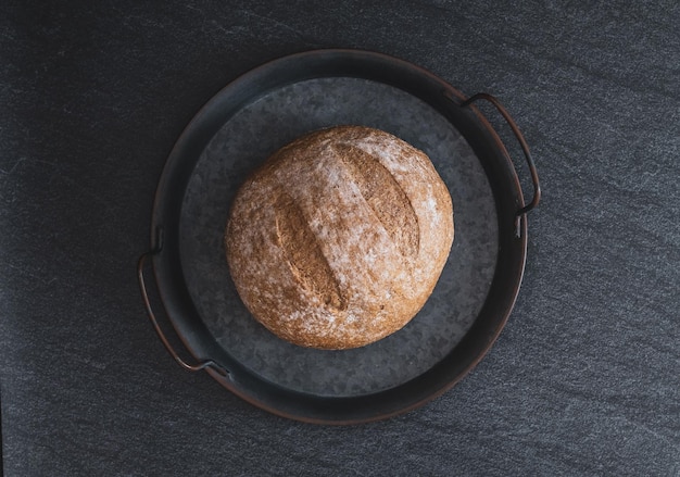 Een rond roggebrood op een zwarte achtergrond