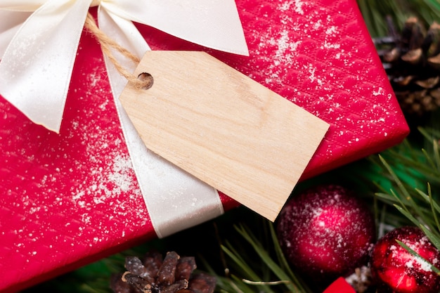 Een rood cadeau met een houten blanco formulier voor tekst een tak van een dennenboom kerst- en nieuwjaarsdecor