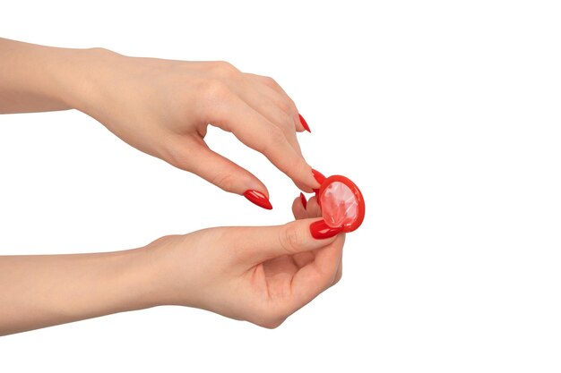 Een rood condoom in de hand van een vrouw met rode nagels geïsoleerd op een witte achtergrond