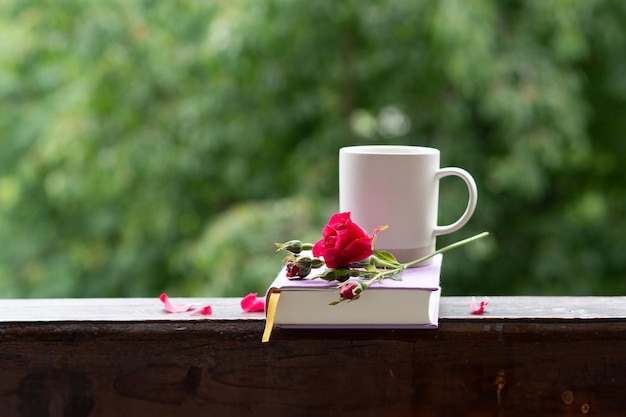 Een roosbloem een boek en een kop koffie Still life op de vensterbank