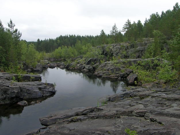 Een rotsachtig landschap met bomen en rotsen op de voorgrond Suna River Poor Porog Waterfall Girvas