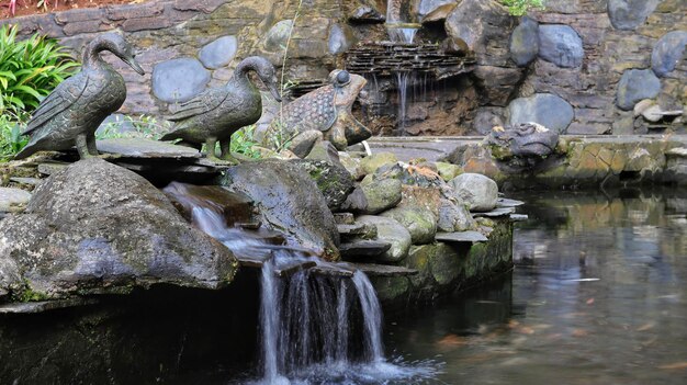 Een rotsachtige vijver met een mini-waterval met enkele dierenbeelden