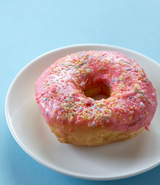 Een roze donut op blauwe achtergrond