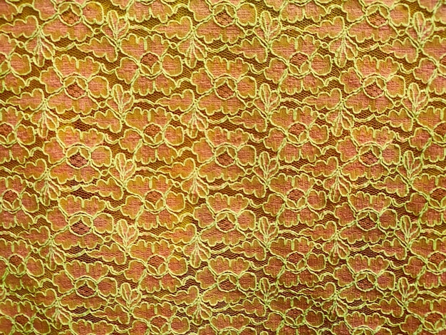 Een roze en gouden kanten stof met een bloemenpatroon.