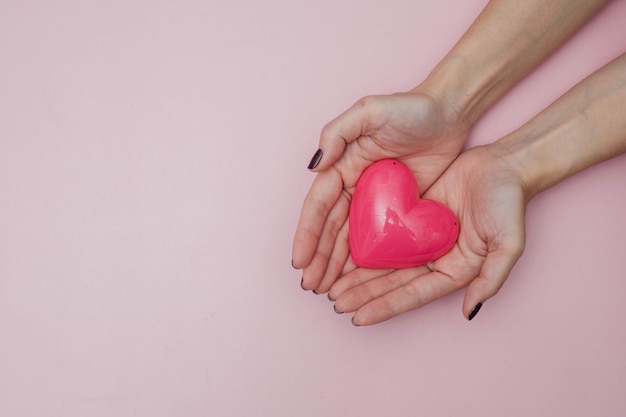 Een roze hart wordt in de palm van handen gehouden