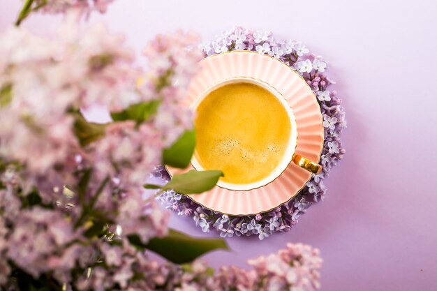 Een roze kop koffie met lila bloemen op een heldere paarse achtergrond