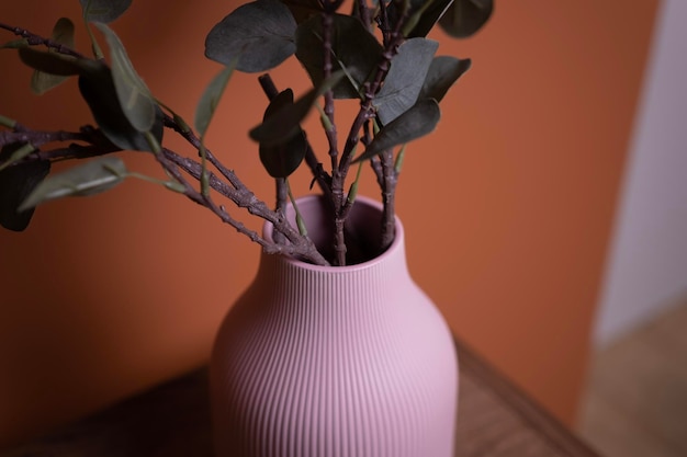 Foto een roze vaas met een groene plant staat op een bruine houten tafel tegen een oranje muur