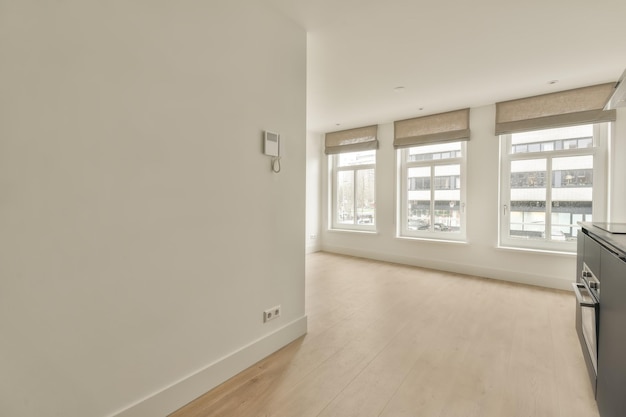 Een ruime lege kamer in lichte kleuren met groot raam in een gezellig appartement