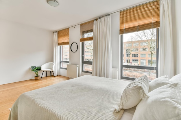 Een ruime slaapkamer met een groot wit bed en een groot raam ernaast in een gezellig appartement